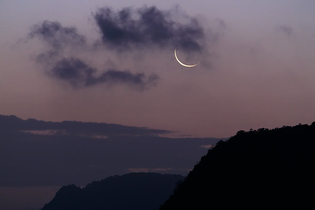 Crescent moon with dark clouds in twilight sky over Phang-nga, Thailand.